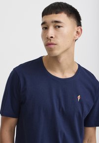 Marineblå bomulds T-shirt med rund hals og korte ærmer, prydet med en lille iskremvaffel broderet på venstre bryst.