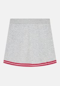 Grå kjol i mjukt material med en ribbad midja och en nederkant med röda och vita randiga detaljer. En enkel A-linjeformad design.