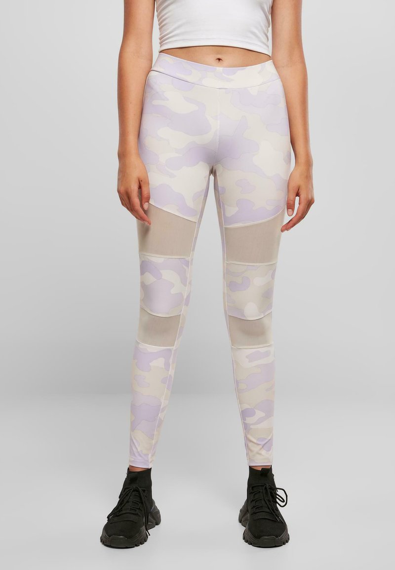 Leggings avec un motif de camouflage beige clair et lavande, dotés de panneaux en mesh, d'une taille haute et d'un design ajusté.
