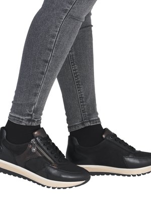 Baskets en cuir noir avec une finition texturée, dotées d'une fermeture éclair sur le côté et d'une semelle beige contrastante. Portées avec un jean skinny gris.