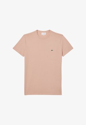 Camiseta de Lacoste en rosa claro hecha de algodón. Manga corta, escote redondo y un pequeño logo de cocodrilo verde en el lado izquierdo del pecho.