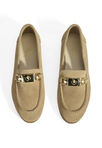 Beige suède instapschoenen met een goudkleurige hardware accent en gestikte details langs de randen. Platte zool met een ronde neus.