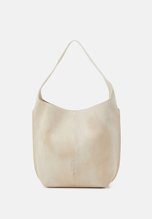 Sac à bandoulière en cuir beige avec une large sangle, une couture verticale subtile et une petite étiquette au centre avant.