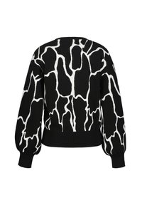 Svart tröja med ett vitt abstrakt mönster, rund halsringning, långa puffärmar och ribbad fåll. Mjuk stickad textur.