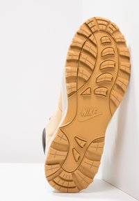 Semelle de sneaker Nike en caoutchouc marron. Profonds motifs pour une meilleure adhérence, design arrondi et motifs texturés. Accents de semelle intermédiaire blanche.
