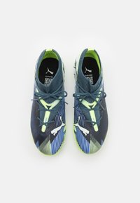 Scarpe da ginnastica blu e verdi con una tomaia testurizzata, strisce a contrasto e un logo prominente sui lati. I lacci testurizzati completano il design.