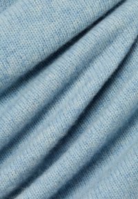 Lichtblauwe gebreide stof met een zachte, gestructureerde oppervlakte. Bevat subtiele variaties in kleur en een consistent ribbelpatroon.