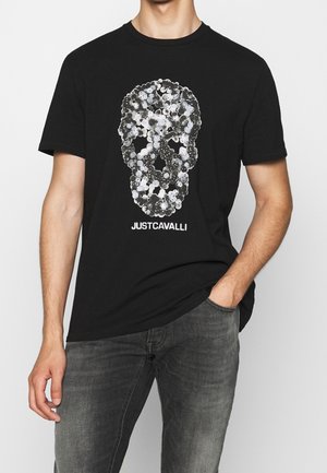 Czarna bawełniana koszulka z nadrukiem czaszki wykonaną z okrągłych wzorów w bieli i szarości. Pod grafiką znajduje się napis „JUST CAVALLI”.