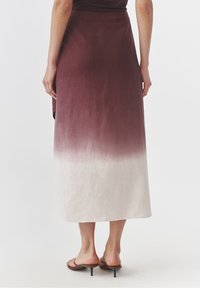 Dlouhá gradientová sukně v odstínu burgundy až bílá, vyrobená z jemného materiálu. Navržena s hladkou texturou a mírně áčkovým střihem.