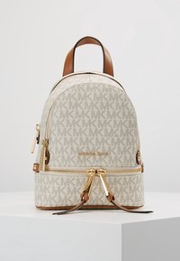 Zaino in tela bianca con motivo a monogramma, dettagli dorati, manici in pelle marrone e zip. Presenta una forma arrotondata e dimensioni ridotte.