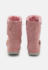 Růžové semišové boty se měkkou umělou kožešinovou podšívkou, výškou po střed lýtek, bočním zipem a prošitými detaily. Šedá gumová podrážka s logem.