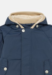 Temno modra jakna z bež rebrastim ovratnikom in podlogo, z zaponkami na pritrditev in stranskimi žepi, strukturiranega dizajna in gladke teksture.