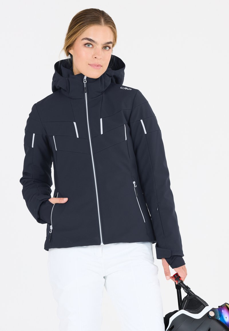 Marineblå softshell jakke med hætte og frontlynlås. Har hvide detaljer, flere lynlåslommer og en tætsiddende pasform. Ideel til udendørs aktiviteter.