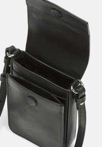 Sac bandoulière en cuir noir avec fermeture à pression, compartiments intérieurs et bandoulière ajustable. Texture lisse, design minimaliste.