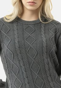 Gray knitted sweater featuring a textured cable pattern with diamond shapes, ribbed crew neckline, and soft, thick fabric.