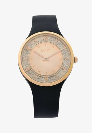 Ronde polshorloge met zwarte band, goudkleurige rand, roze wijzerplaat, kristallen accenten rond de wijzerplaat en de merknaam "LIU·JO" in het midden.