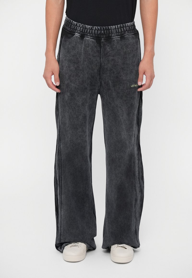 Graue weit geschnittene Hose aus weichem Stoff mit feiner Textur. Mit einem elastischen Bund und einem goldenen Logodetail auf der linken Seite.