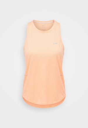 Bezrękawnik treningowy Nike w kolorze brzoskwiniowym, z okrągłym dekoltem i małym odblaskowym logo na lewej piersi.