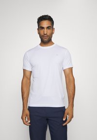 Witte t-shirt met korte mouwen, gemaakt van een gladde, lichte stof. Heeft een ronde halslijn en een klein merklogo op de borst.