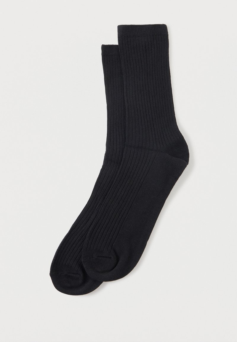 Paire de chaussettes noires côtelées mi-mollet posées à plat avec un talon et un orteil renforcés sur fond blanc.