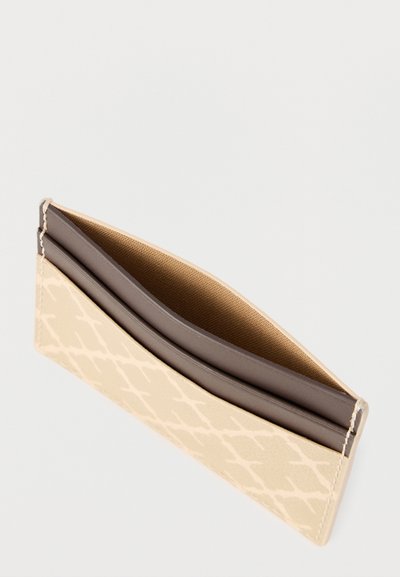 Λεπτό μπεζ πορτοφόλι καρτών με διακριτικό μοτίβο, καφέ εσωτερική επένδυση και δύο θήκες καρτών σε λευκό φόντο.
