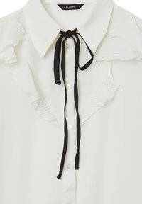 Blusa bianca con colletto a punta, caratterizzata da legature in nastro nero e pieghe testurizzate lungo i bordi del colletto. Chiusura frontale con bottoni.
