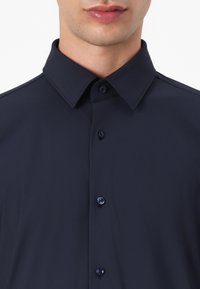 Navy-blaues Hemd mit steifem Kragen, gefertigt aus glattem Stoff und ausgestattet mit fünf passenden Knöpfen. Keine Muster oder Akzente sichtbar.
