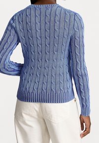 Blå stickad tröja med flätmönster, ribbade ärmslut och nederkant. Den har olika nyanser av blått, en strukturerad finish och en figurnära passform.