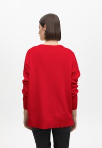 Roter, übergroßer Pullover mit langen Ärmeln, gerippten Bündchen und Saum, runder Ausschnitt und glatter Textur. Rückansicht gezeigt.
