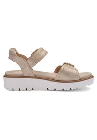 Sandale beige à bout ouvert avec deux brides cloutées, semelle épaisse blanche et soutien de la cheville, conçue pour un usage décontracté.