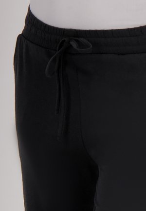 Zwarte joggingbroek met een elastische tailleband en trekkoord. Glad materiaal, aansluitend bij de taille en taps toelopend naar de enkels.