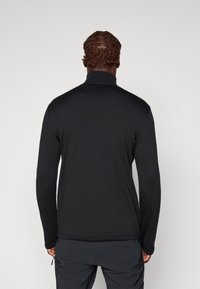 Čierna fleecová bunda na zips s vysokým golierom, dlhými rukávmi a textúrovaným povrchom. Minimalistický dizajn, bez viditeľných log alebo akcentov.