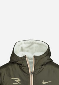 Veste zippée vert olive avec une capuche et un intérieur doublés en polaire. Comprend des éléments en métal doré et un logo sur la poitrine. Texture extérieure lisse.