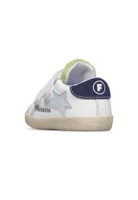 Zapatilla de deporte blanca de piel con una correa de Velcro, acentos en azul y verde, detalle de estrella en azul claro y suela de goma texturizada.