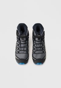 Chaussures de randonnée montantes noire et grise avec tige en maille, col rembourré et semelle extérieure bleue. Elles disposent d'un système de laçage et d'accents réfléchissants.