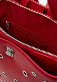Roter Leder-Handtascheninnenraum mit einem Reißverschlussfach, Metallbeschlägen und einer glatten Textur. Mit passendem Futter und Reißverschlussdetails.