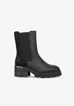 Stivale alla caviglia in pelle nera con un pannello in tessuto nero testurizzato, suola in gomma spessa e un accento argentato sul tallone. Presenta un design a punta rotonda.