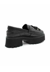 Zwarte leren instappers met een chunky gekartelde zool, voorzien van decoratieve veters en stiksels, met metalen hardware aan de achterkant.