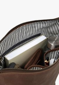 Braune Ledertasche mit einem gestreiften Stofffutter, die ein Notizbuch, eine Geldbörse, eine Wasserflasche und Stifte enthält.