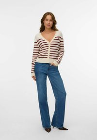 Striped cardigan in cream with maroon stripes, V-neck, button closure, ribbed cuffs; paired with high-waisted blue denim flared jeans.
