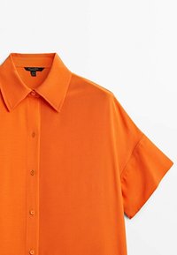 Short-sleeve orange shirt made from lightweight fabric; features a pointed collar and front button closure with matching buttons.