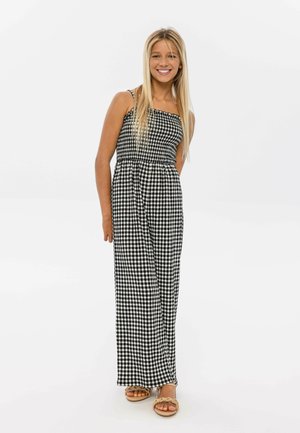 Combinaison à motif vichy noir et blanc avec des bretelles fines, taille cintrée et jambes larges, fabriquée dans un tissu léger.
