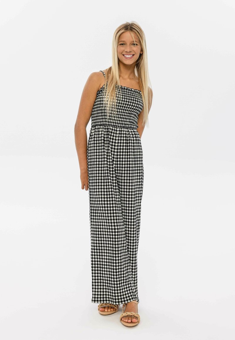 Combinaison à motif vichy noir et blanc avec des bretelles fines, taille cintrée et jambes larges, fabriquée dans un tissu léger.