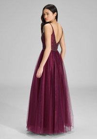 Bordowa sukienka formalna z dopasowanym koronkowym topem ozdobionym koralikami i pełną spódnicą z tiulu. Posiada głęboki dekolt na plecach oraz cienkie ramiączka.