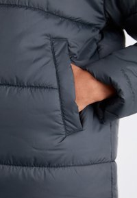 Tumed sinine puffjakki, millel on pehme ja läikiv viimistlus. Omab külje taskut ja tikitud detaile mööda keha, et lisada jaoks tekstuuri.