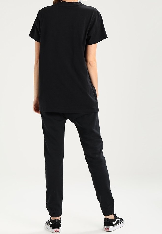 Svart bomullströja med korta ärmar, ihop med svarta joggerbyxor. Byxorna har elastiska muddar och en lös passform för komfort.