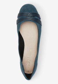 Blå mocka ballerinaskor med en knuten läderrem över tån. Inredningen är beige med märkets logotyp präglad.