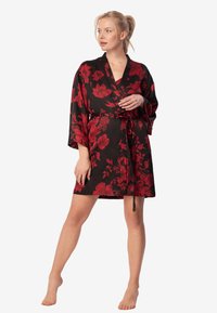 Czarny kimono w kwiaty z czerwonymi wzorami, z szerokimi rękawami, wiązaniem w talii i długością do połowy uda. Gładka faktura materiału.