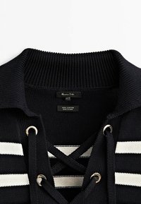 Pull en maille noir avec col côtelé, rayures horizontales blanches, laçage croisé à travers des œillets argentés et une étiquette Massimo Dutti.