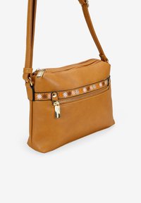 Bolso cruzado de cuero color tostado con un bolsillo frontal con cremallera, acento bordado floral y correa ajustable. Cuenta con una textura suave y herrajes dorados.